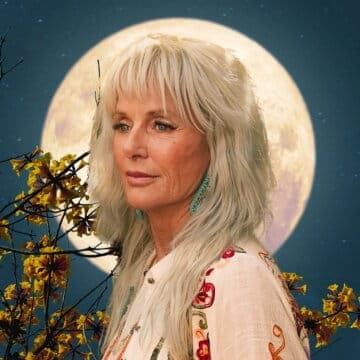 A woman with long hair stands in front of a full moon, surrounded by blooming branches against a starry night sky.
